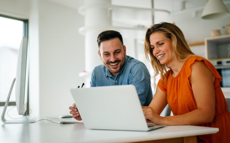 Woman and man behind their laptop looking at dental financing options