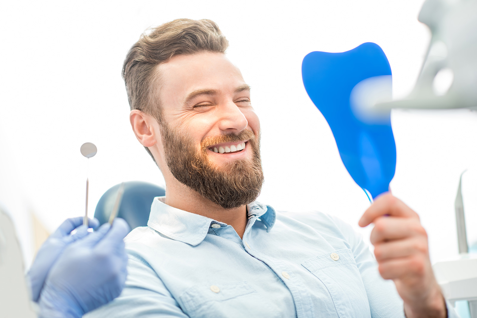 Man in a dental chair smiling, showing the importance of quality dental restorations